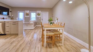 Una cocina amplia con armarios de madera, una mesa de comedor con sillas y una lámpara colgante moderna.