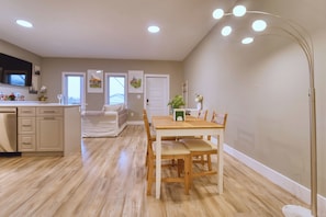 A spacious kitchen with wooden cabinets, a dining table with chairs, and a modern pendant light.