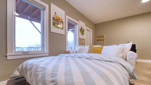 Un dormitorio con una cama grande, una ventana y obras de arte en la pared.