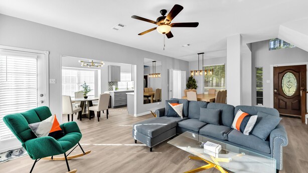 A modern living room with a sectional sofa, a rocking chair, and a glass coffee table. - 5BR Pool House • Just 15 Min to DFW Airport (Lewisville)