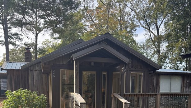 Ein rustikales Holzhaus mit Veranda und der auf der Tür deutlich sichtbaren Nummer 245.