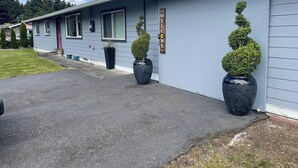 A building with a 'WELCOME' sign, a driveway, and potted topiary plants.