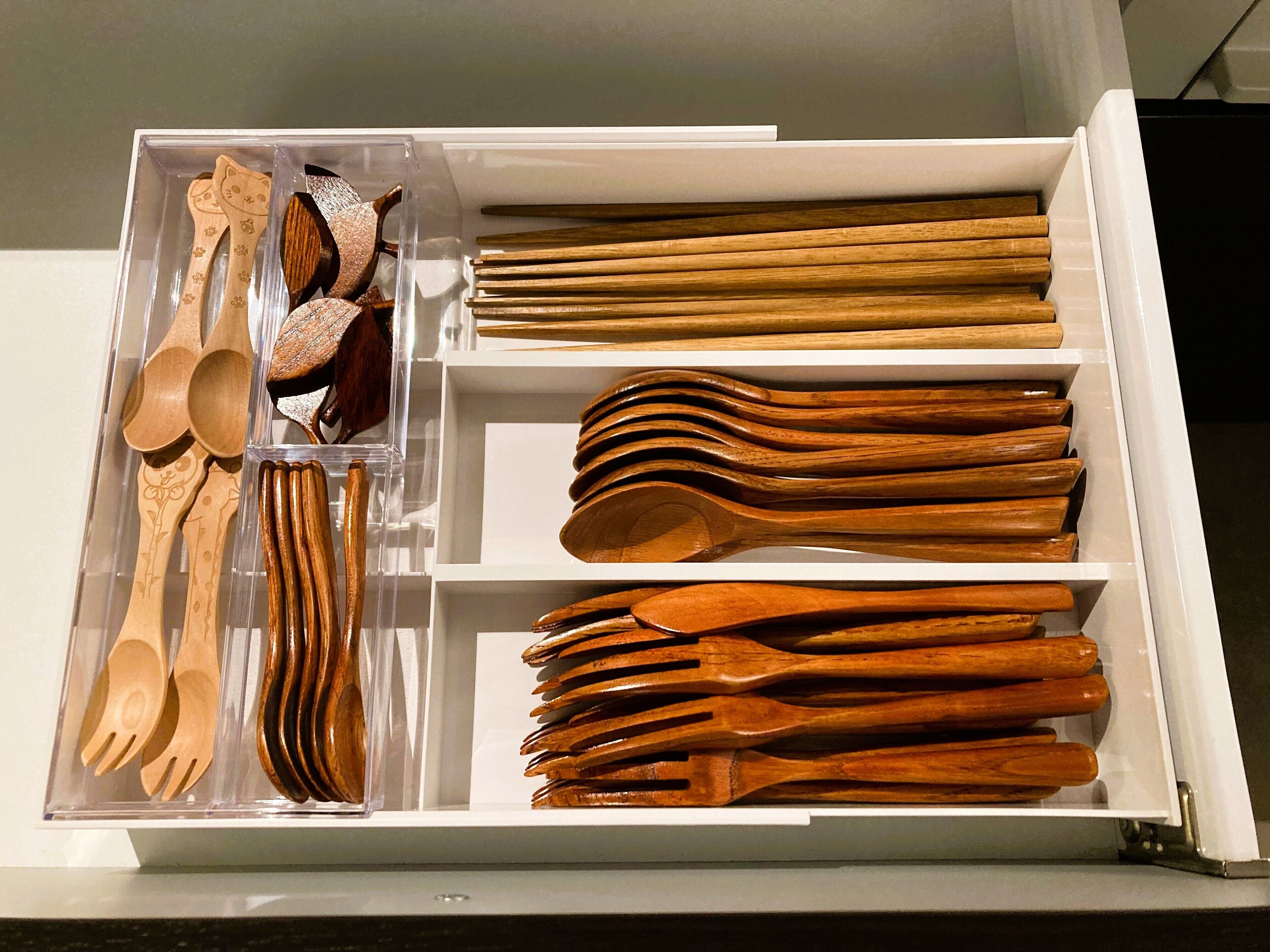 Un cajón con varios utensilios de madera, como cucharas, tenedores y palillos.