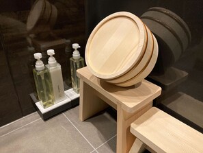 A wooden vanity with a mirror and a wooden stool. There are three bottles of liquid soap on a white stand. - IO2 Misono no Oyado RO (Wakayama)