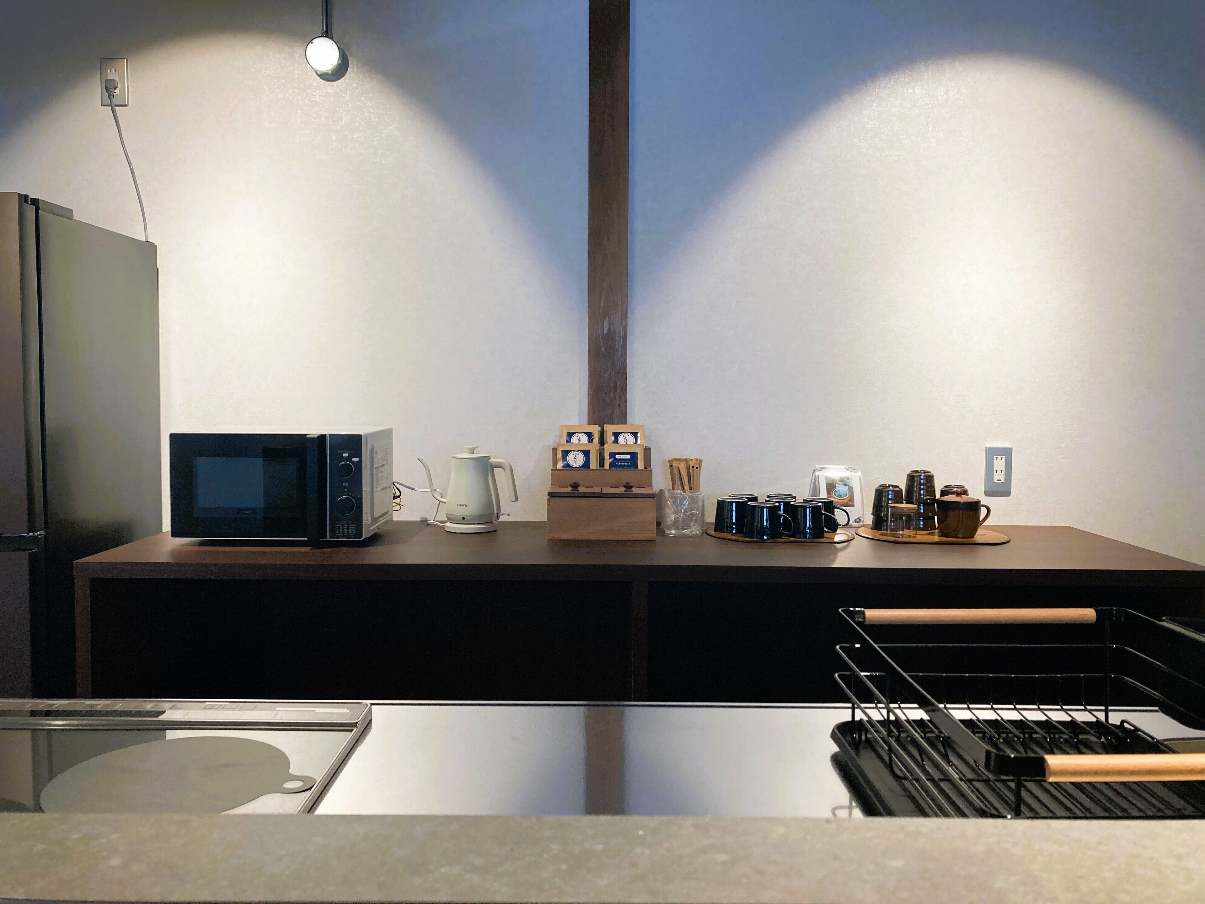 Une cuisine équipée d’un four à micro-ondes, d’une machine à café et de différentes tasses disposées sur le comptoir.
