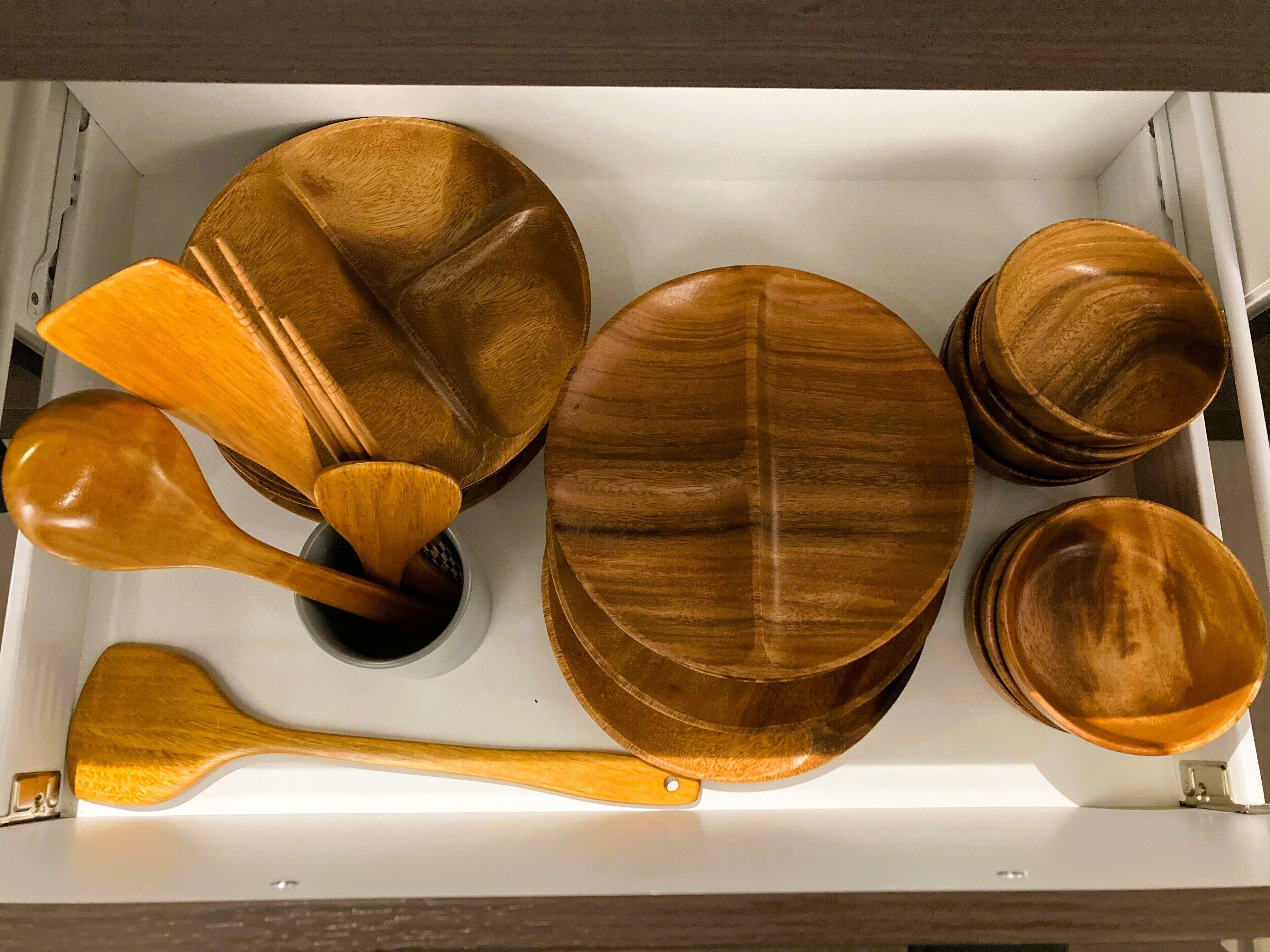 A drawer containing various wooden kitchen utensils and dishes.
