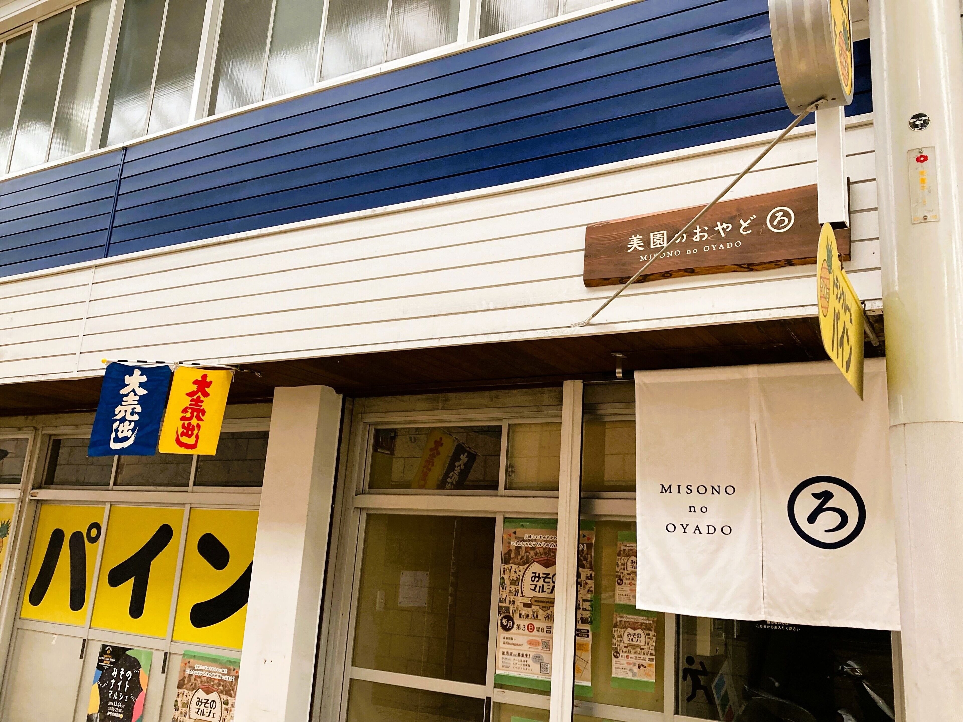 Un bâtiment avec un toit bleu et une enseigne sur laquelle on peut lire « Misono no Oyaido ».