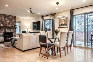 A spacious living room with a fireplace, a dining area with a glass table, and large windows offering a view of the outdoors. - Cozy 3-bedroom 3bath home with amazing views & incredible location in Boulder. (Boulder)
