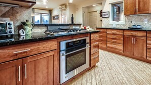 Een keuken met houten kastjes, een roestvrijstalen oven en een granieten aanrecht.