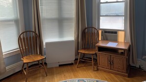 Habitación de esquina con dos sillas de madera, una mesita pequeña y un radiador.