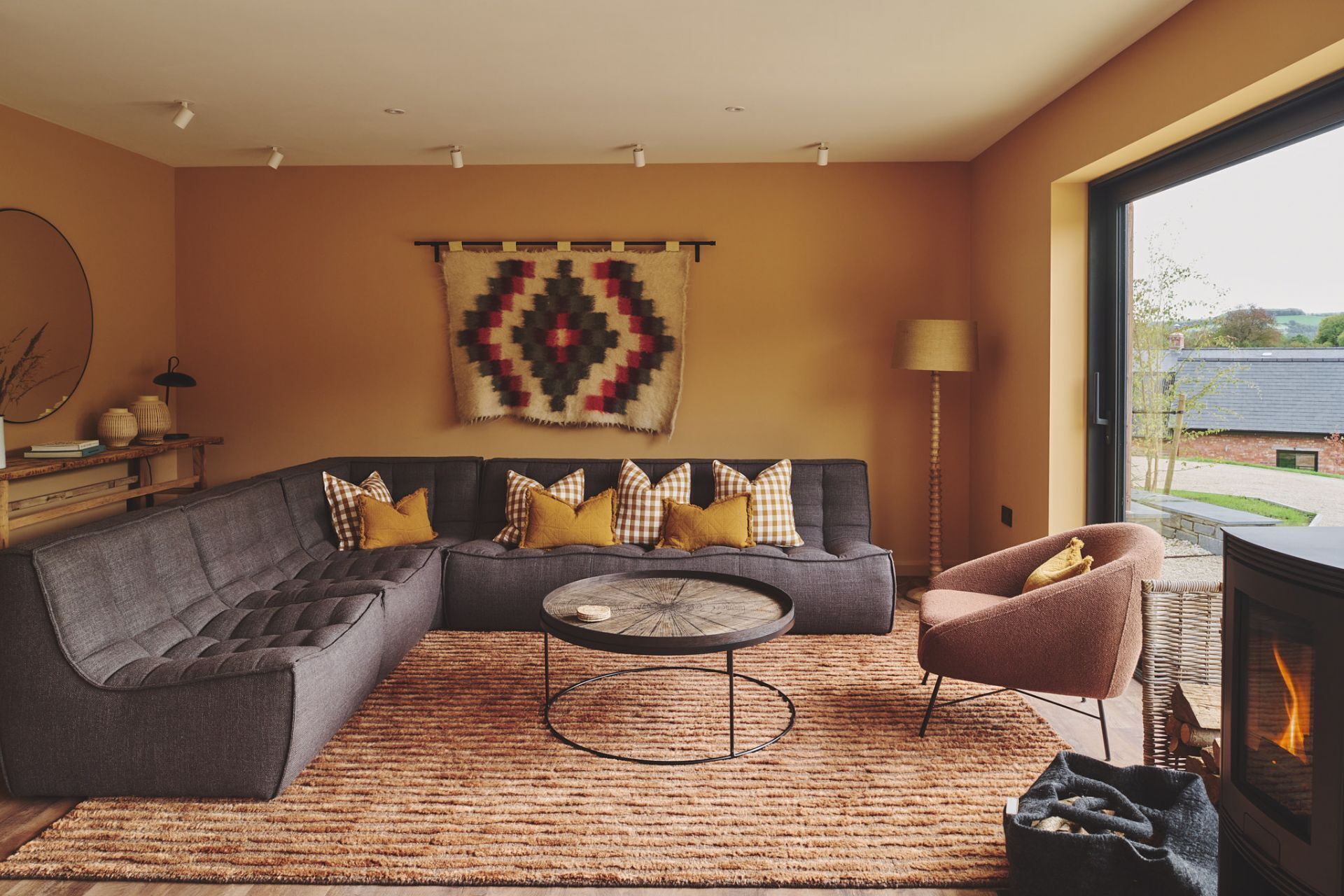 A modern living room with a sectional sofa, a round coffee table, and a fireplace.
