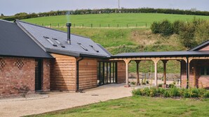 Un bâtiment en briques doté d’un toit en pente et d’un espace extérieur abrité, agrémenté d’une pergola.