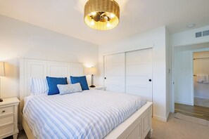 A bedroom with a bed, bedside tables, a wardrobe, and a hanging light fixture. - New: Luxury Beachfront Penthouse, Many Ocean Views, Steps 2 beach and harbor, Marina del Mar 402A (Oceanside)