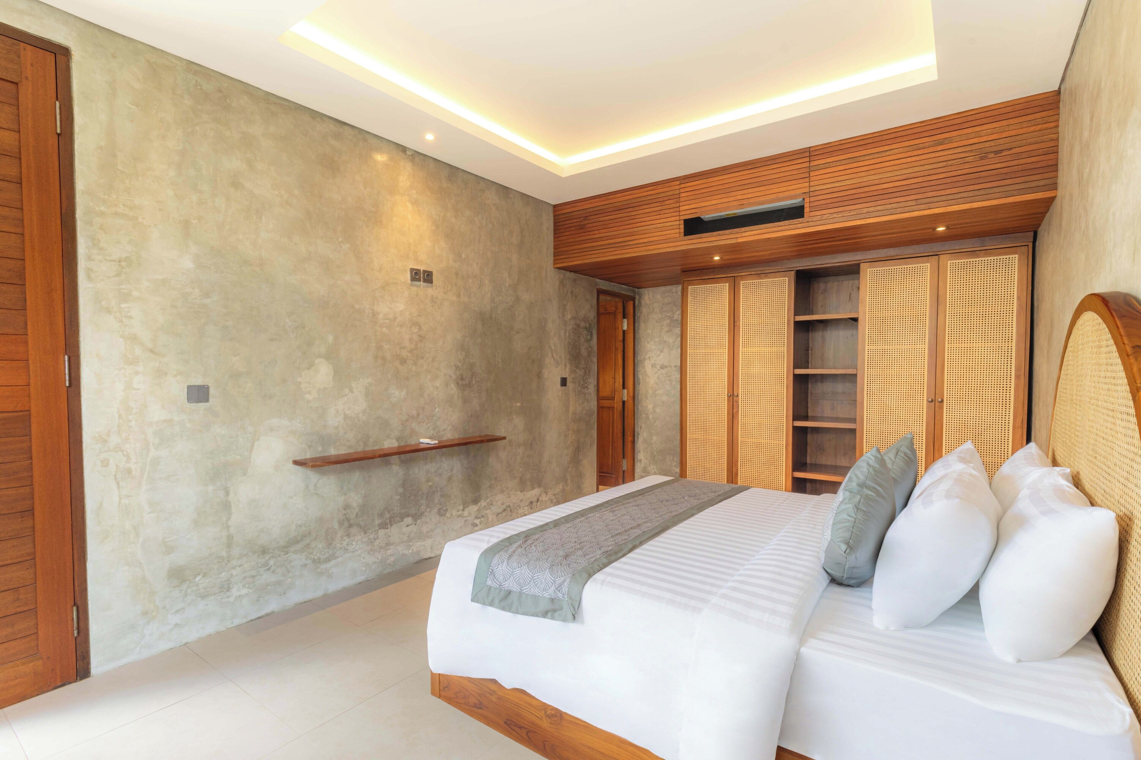 A modern bedroom with a large bed, wooden headboard, and built-in shelving.