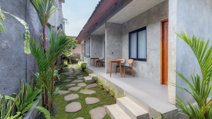 Una casa moderna con porche cubierto, escalones de piedra y mobiliario exterior.