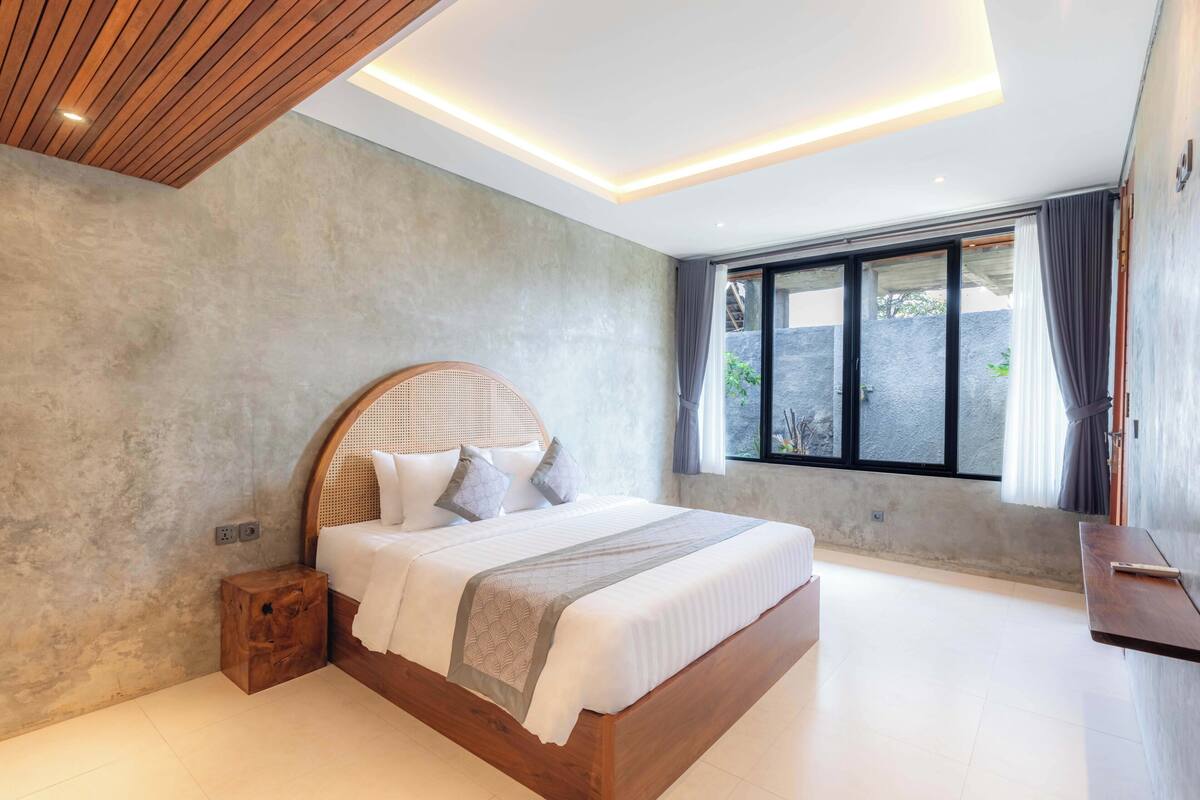Une chambre moderne avec un lit en bois, une petite table de chevet et une grande fenêtre avec des rideaux.