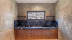 Una cocina compacta con encimera de mármol oscuro, armarios de madera y salpicadero de azulejos.