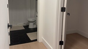 A bathroom with a toilet, shower curtain, and a small rug on the floor. - Cozy 2BR/2BA Retreat 5 Min from EWR, 15 Min to NYC (Elizabeth)