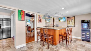 Una cocina moderna con una isla central, zona de bar y un refrigerador.