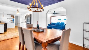 Una cocina moderna con armarios blancos, una mesa de comedor de madera y una araña.