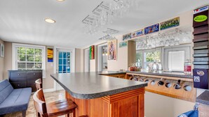 Una cocina moderna con una isla central, armarios de madera y una zona de bar con cristalería.