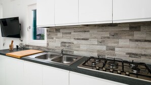 Una cocina moderna con encimera de granito, pileta de acero inoxidable y cocina a gas.