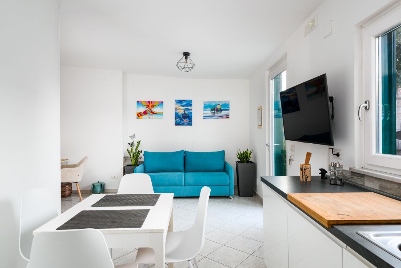 A modern kitchen with a dining area, a blue sofa, and artwork on the walls.