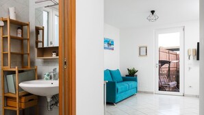 Un baño con estante de madera, lavamanos y espejo.