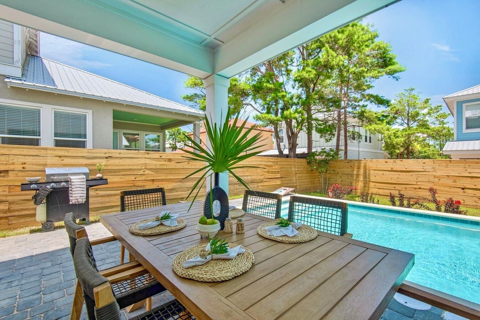 Een houten terras met een pooltafel, een barbecue en een potplant.