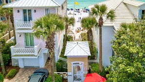A beachfront property with multiple buildings, a beach with people, and palm trees. - Vibe Out: Private beach steps away, Heated pool, Golfcart, Game room, Bunk rooms (Miramar Beach)