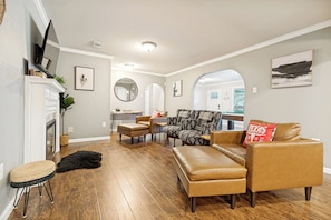 A spacious living room with a fireplace, leather sofas, and a dining area in the background.
