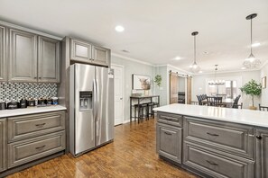 A modern kitchen with stainless steel appliances, grey cabinetry, and a wooden floor.
