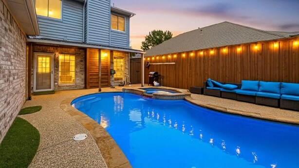 A backyard with a swimming pool, a barbecue area, and a seating area with blue cushions. - Modern 5BR/2.5BA w/Private Pool  Sleeps 16 ppl (Allen)
