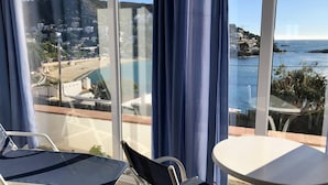 A balcony with a view of a beach and sea, a table, and two chairs. - Apartment in Roses on the seafront.MONTEMAR (Roses)