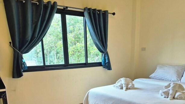 Una habitación de hotel con una cama, una mesita y un ventanal con cortinas.
