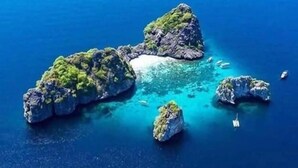 Vista aérea de una pequeña isla con aguas azul cristalina y terreno rocoso.
