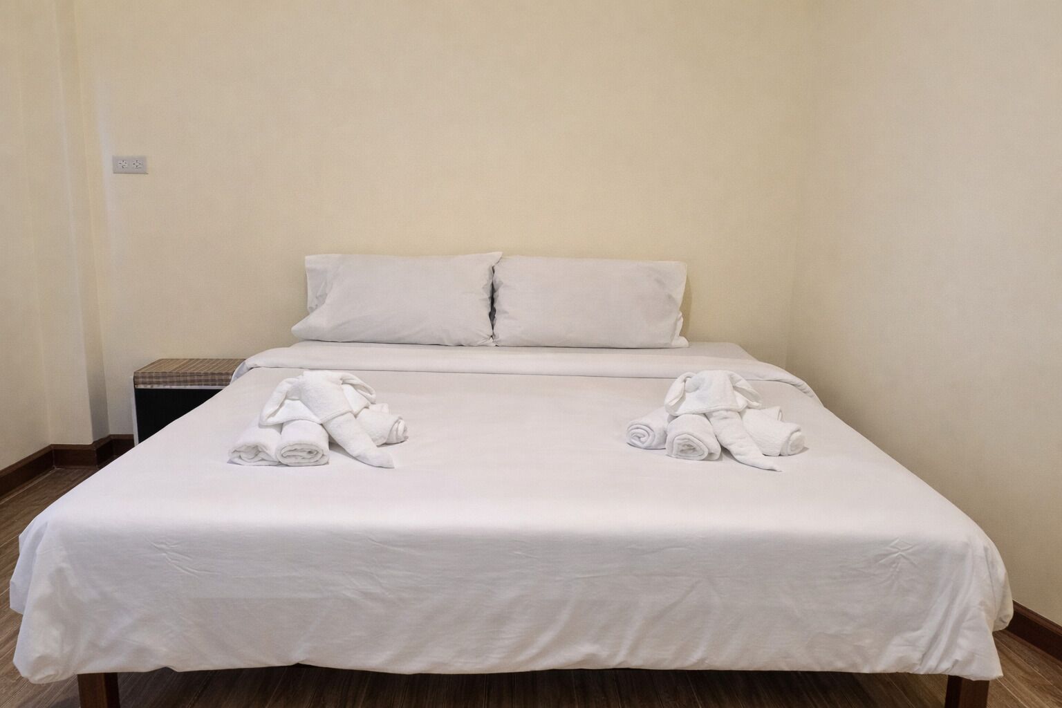 A neatly made bed with white linens and towels folded at the foot.