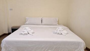 A neatly made bed with white linens and towels folded at the foot.