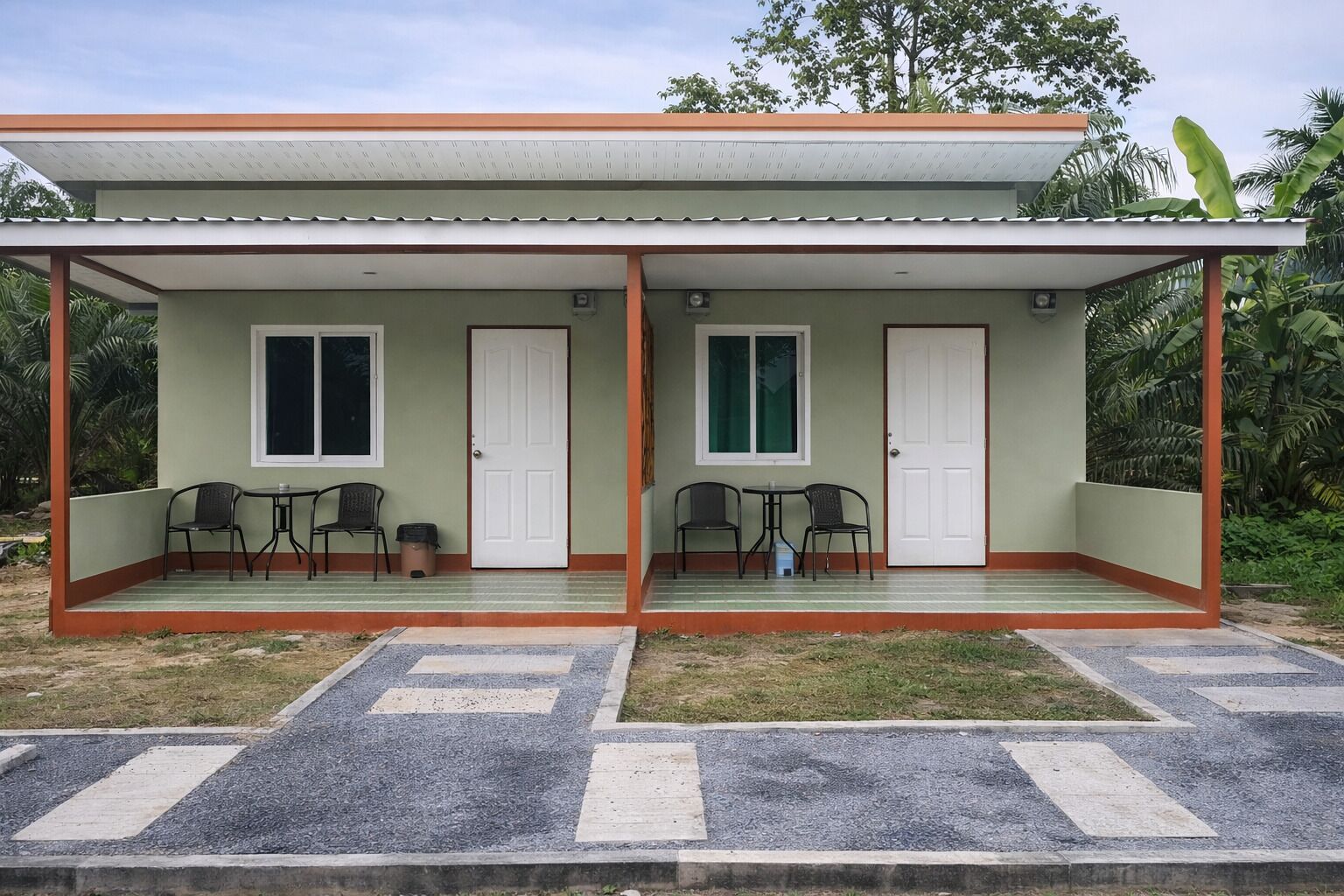 A two-story building with a covered porch, two doors, and two tables with chairs.