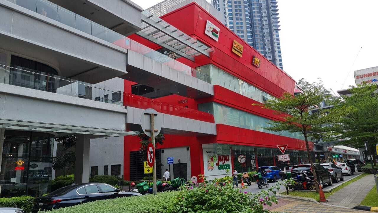 A multi-story building with a red and white facade, featuring a large glass entrance and a visible sign for a restaurant.