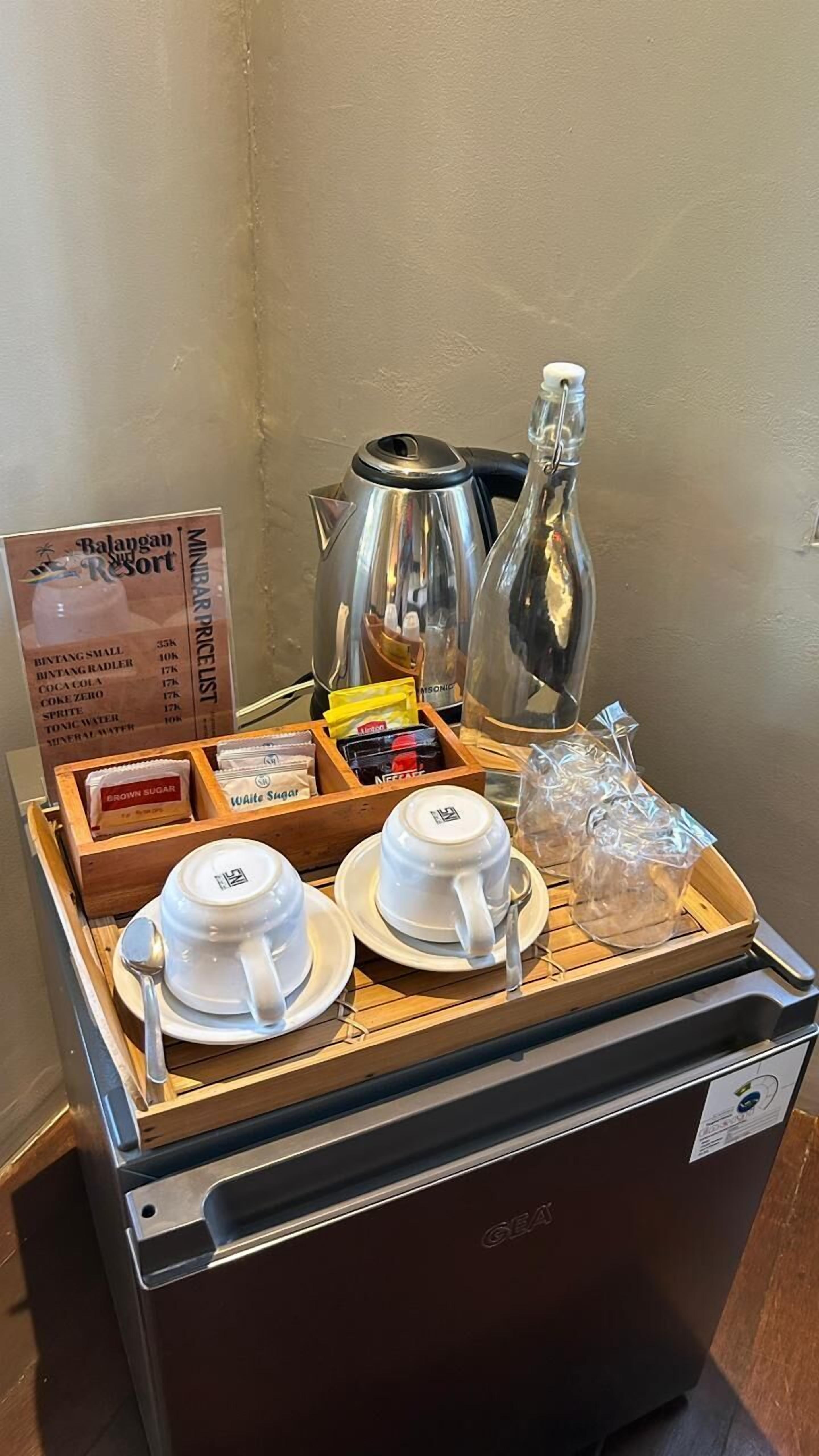 A coffee station with a coffee maker, sugar packets, a thermos, and a sign listing prices.
