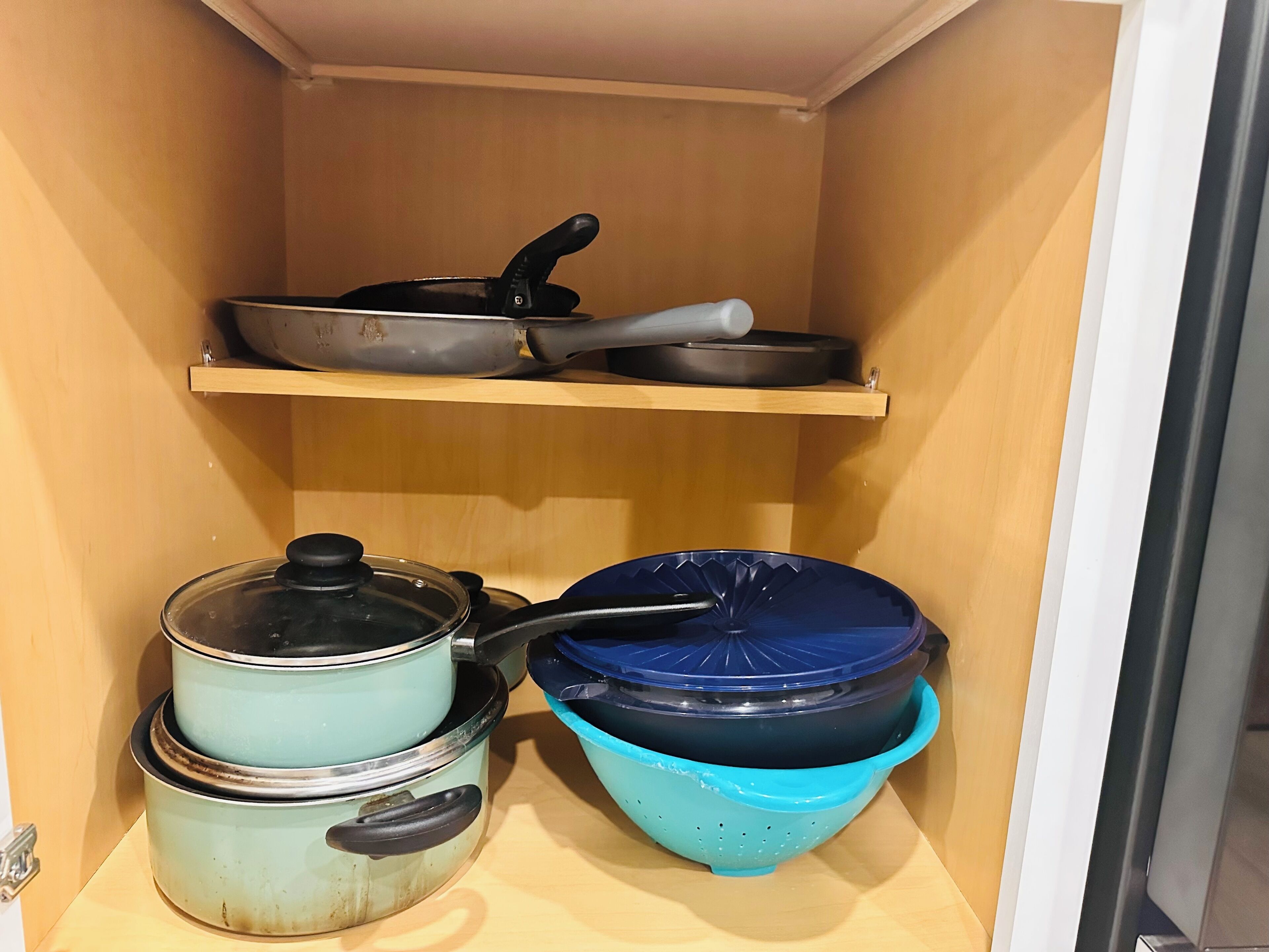 Un armario de cocina con ollas y sartenes.