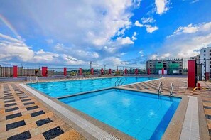 Ein Schwimmbecken mit Fliesen umrandet und einem Zaun.