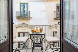 A balcony with two chairs, a table with a plate of food and drinks, and potted plants on the railing. - Marinella Mia House (Sorrento)