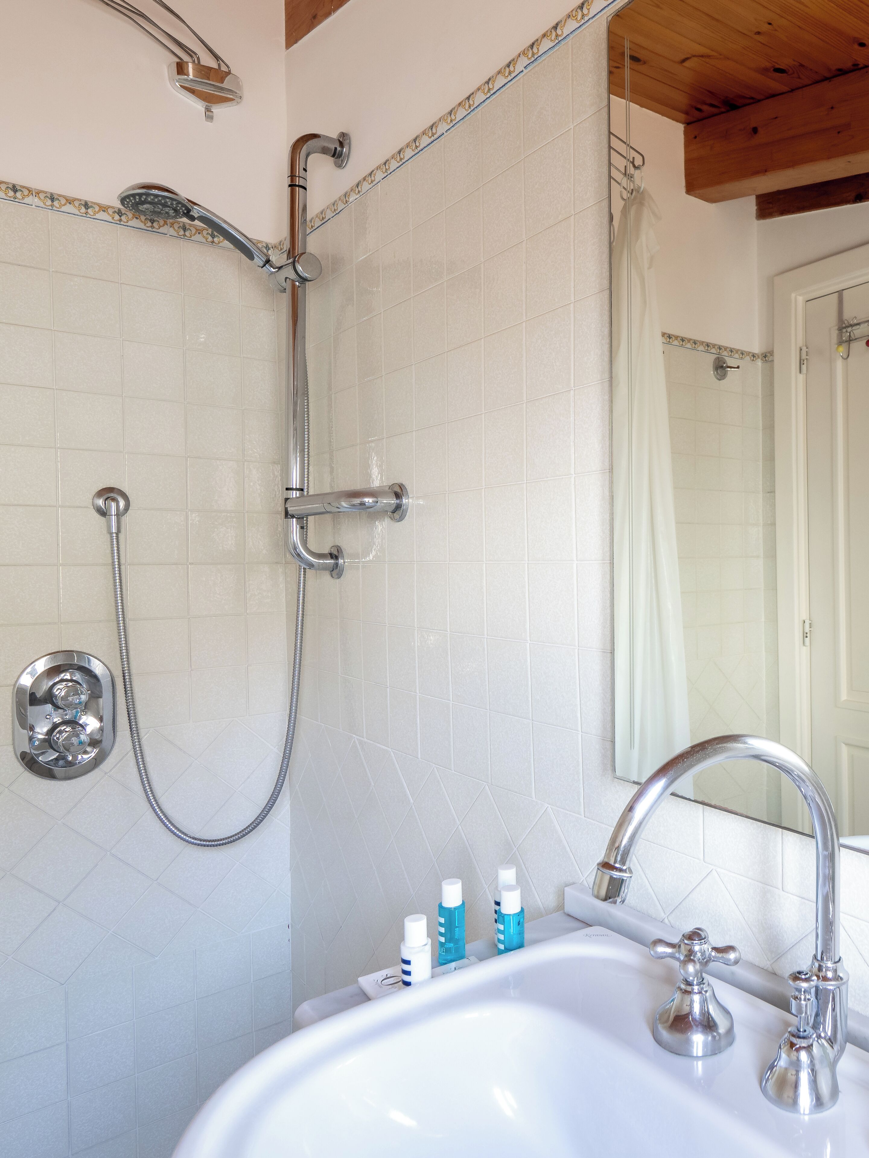 Une salle de bain avec une douche, un lavabo et un miroir.