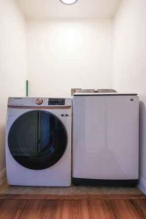 A laundry room with a front-loading washing machine and a top-loading dryer. - Cozy and Spacious 5 bedrooms House at Duplex (Vernon)