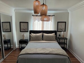 Ein Schlafzimmer mit einem großen Bett, zwei Nachttischen, einem Spiegel und einem Fenster mit Vorhängen.