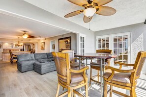 A spacious living area with a gray sofa, wooden chairs, a dining table, and a ceiling fan. - Harbor Towers – Bayfront Luxury with Pool & Tennis (Sarasota)