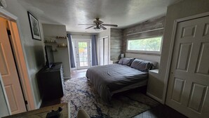 Une chambre à coucher avec un lit, un ventilateur de plafond, une fenêtre et une porte.