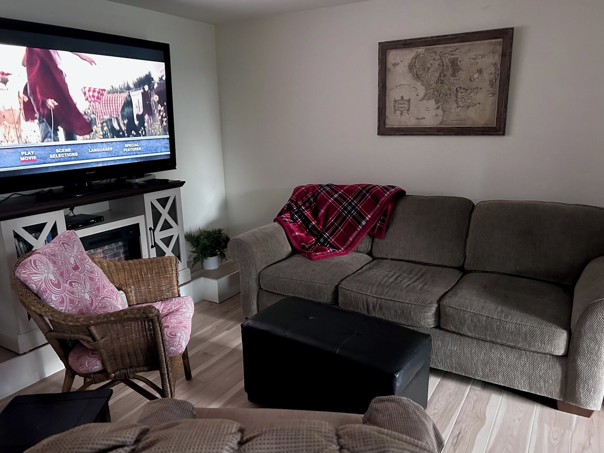 Ein Wohnzimmer mit Fernseher, einer Couch, einem Sessel und einem kleinen Tisch.